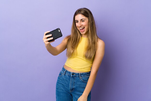 Mujer joven en púrpura aislado haciendo un selfie