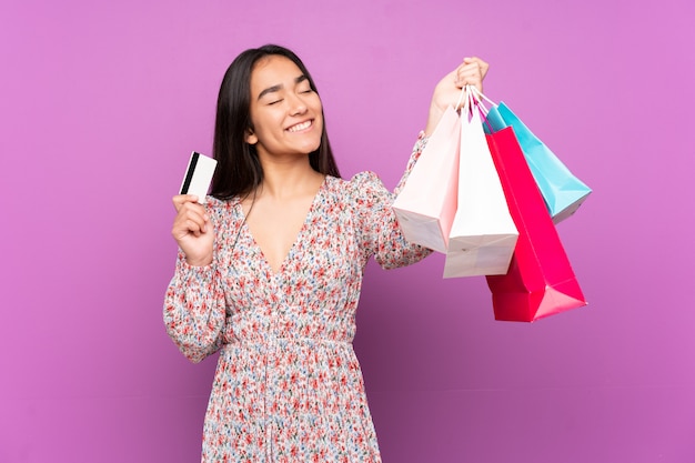 Mujer joven en púrpura con bolsas de compra y una tarjeta de crédito