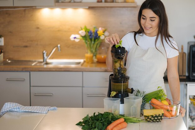 Mujer joven puso apio en el proceso de jugo de hacer bebida saludable lugar para el texto