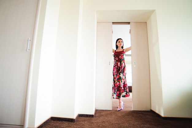 Mujer joven que abre la puerta en la habitación moderna.