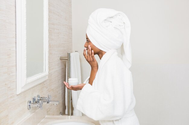 Mujer joven que aplica la crema hidratante