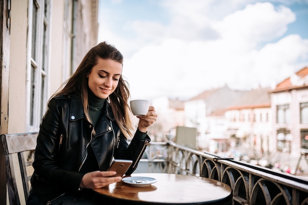 Mujer joven que bebe una taza de café al aire libre.