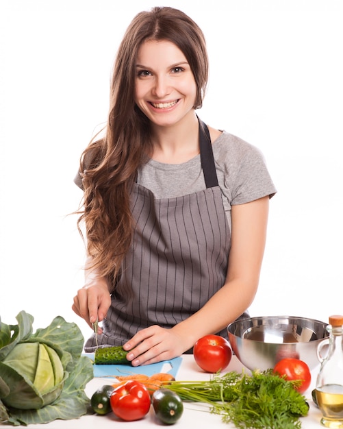 Mujer joven que cocina en la cocina. Comida sana