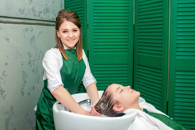 Mujer joven que consigue un lavado de pelo en salón de belleza.