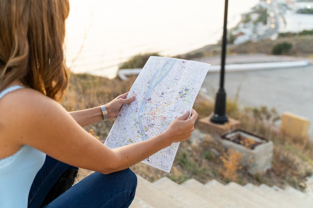 Foto mujer joven que consulta un mapa de la ciudad con su teléfono móvil.