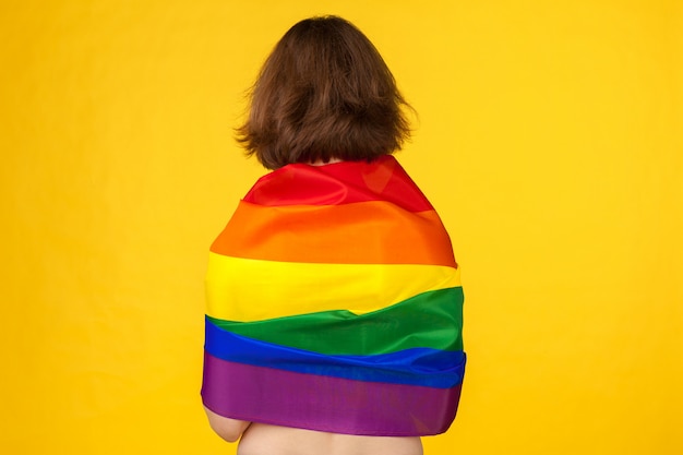 Mujer joven que cubre con la bandera del orgullo LGBT