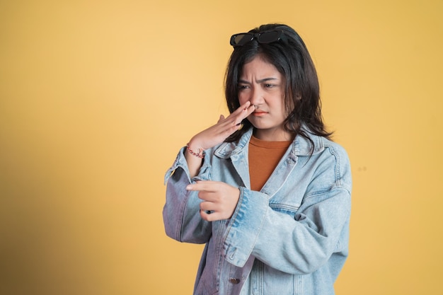 Mujer joven que cubre la nariz con el dedo cuando huele mal