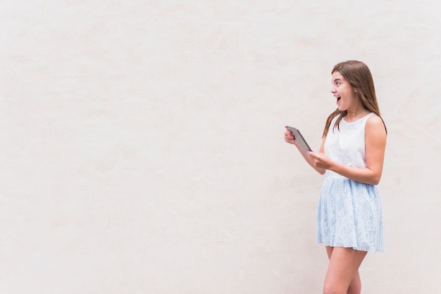 Foto mujer joven que se divierte con la tableta en el fondo blanco