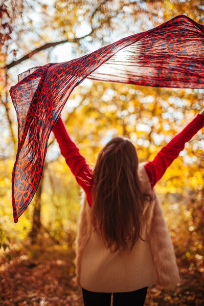 Mujer joven que se ejecuta con una bufanda en el bosque