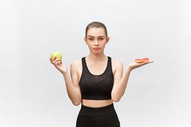 Mujer joven que elige entre el postre y el concepto de comida de dieta de manzana.