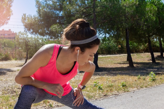 Mujer joven que se extiende después de correr mientras escucha música con auriculares Estilo de vida saludable