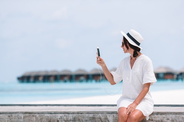 Mujer joven que habla en el teléfono durante vacaciones en la playa tropical