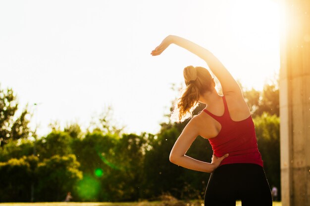 Foto mujer joven que hace algunos ejercicios de calentamiento antes de correr.