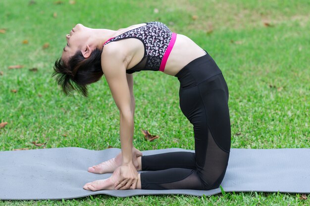 Mujer joven que hace yoga en el parque