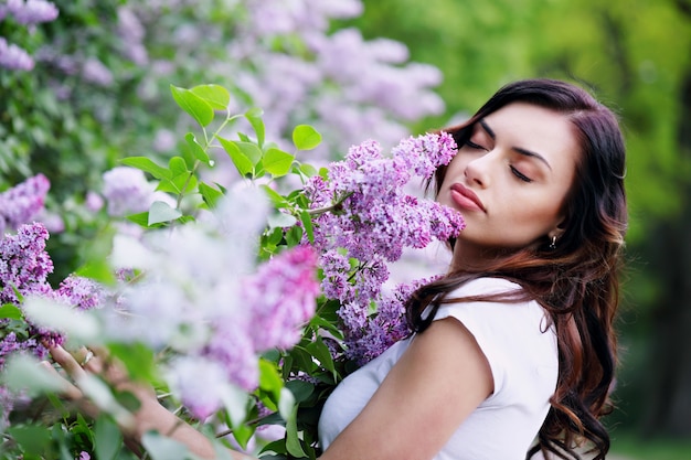 Mujer joven que huele una lila
