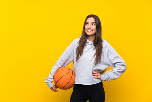 Mujer joven que juega al baloncesto que mira para arriba mientras que sonríe