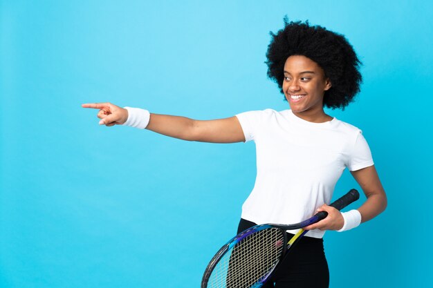 Mujer joven que juega a tenis sobre fondo aislado