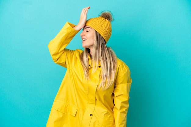 Mujer joven que llevaba un abrigo impermeable sobre fondo azul aislado se ha dado cuenta de algo y tiene la intención de la solución