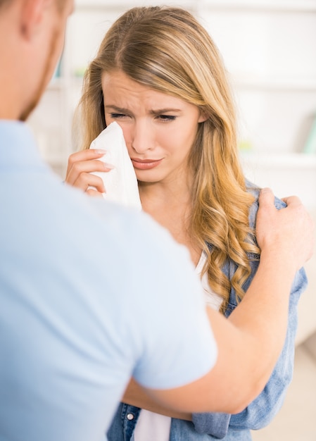 Mujer joven que llora mientras que el marido la calma.