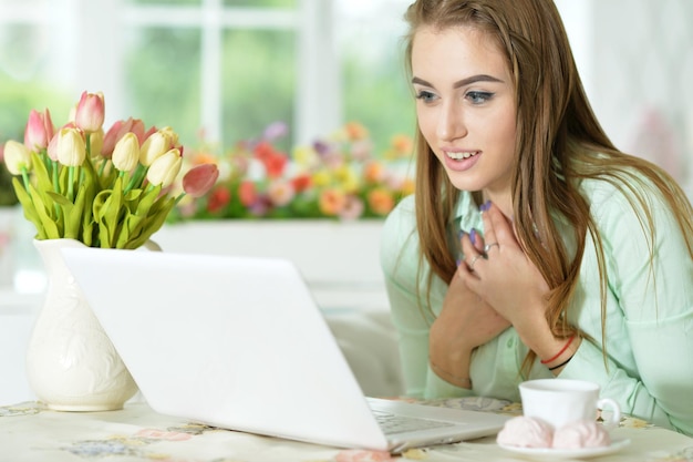 Mujer joven que mira la computadora portátil