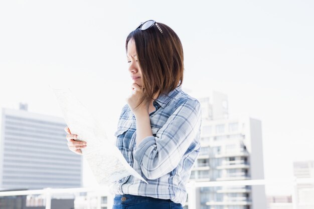 Mujer joven que mira el mapa para la dirección al aire libre