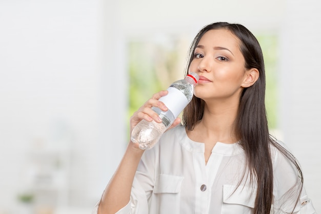 Mujer joven que muestra una botella de agua