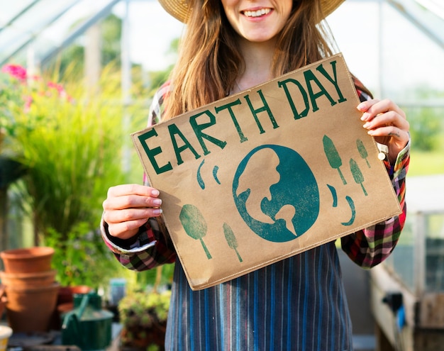 Mujer joven que muestra el cartel del Día de la Tierra