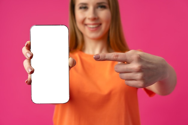 Foto mujer joven que muestra el teléfono inteligente con pantalla blanca aislada sobre fondo de color