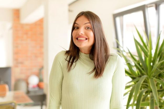 Mujer joven que parece feliz y tonta con una amplia sonrisa chiflada y los ojos bien abiertos