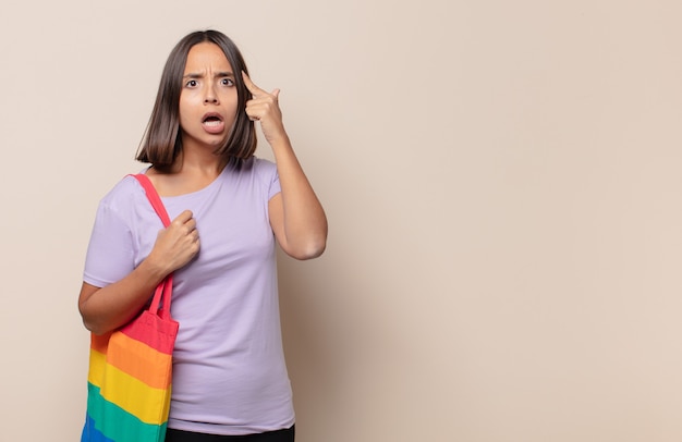 Mujer joven que parece sorprendida, con la boca abierta, conmocionada, dándose cuenta de un nuevo pensamiento, idea o concepto