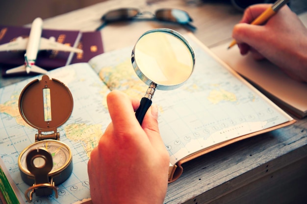 Foto mujer joven que planea sus vacaciones con un mapa de viaje está buscando el próximo destino con una lupa en la mano tendencias de trotamundos wanderlust y concepto de vacaciones enfoque en la lupa