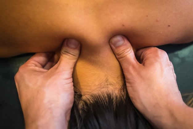 Una mujer joven que recibe un masaje en el cuello con dos dedos por parte de un fisioterapeuta Fisio osteopatía