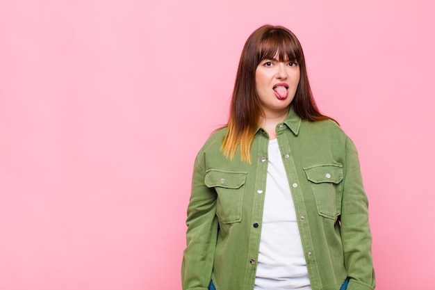 Mujer joven que se siente disgustada e irritada, sacando la lengua, disgustando algo desagradable y asqueroso