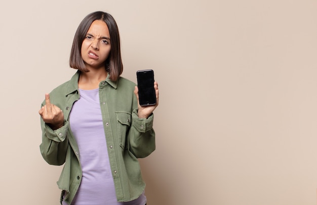 Mujer joven que se siente enojada, molesta, rebelde y agresiva, moviendo el dedo medio, contraatacando