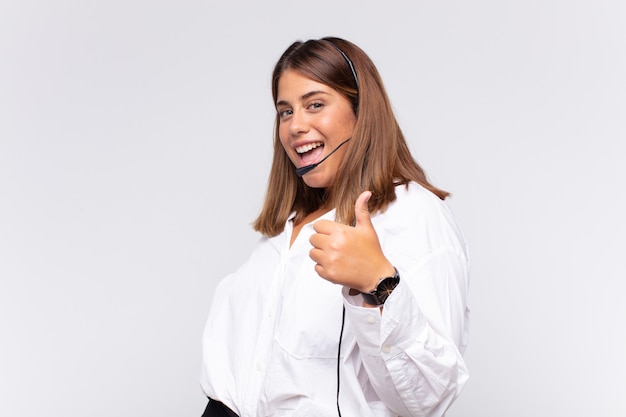 Mujer joven que se siente orgullosa, despreocupada, segura y feliz, sonriendo positivamente con los pulgares hacia arriba