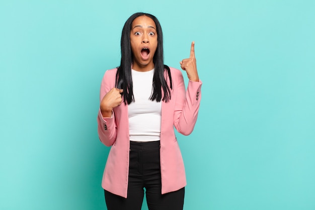 Mujer joven que se siente orgullosa y sorprendida, apuntando a sí misma con confianza, sintiéndose como el número uno exitoso