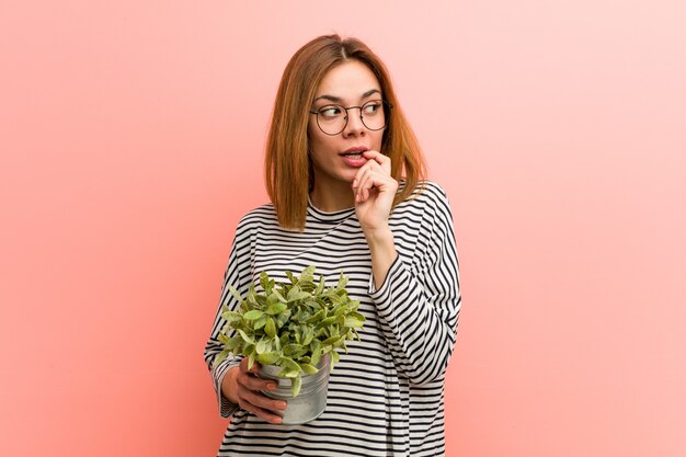 La mujer joven que sostenía una planta se relajó pensando en algo que miraba un espacio de la copia.