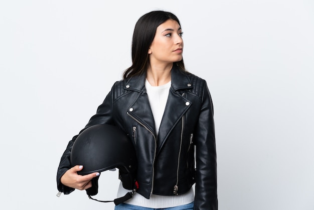 Foto mujer joven que sostiene un casco de motocicleta sobre el lado de aspecto blanco aislado