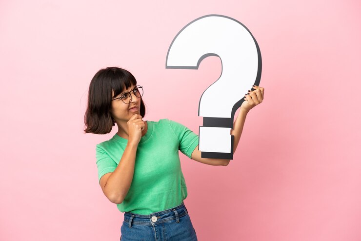 Foto mujer joven que sostiene un icono de signo de interrogación y tiene dudas