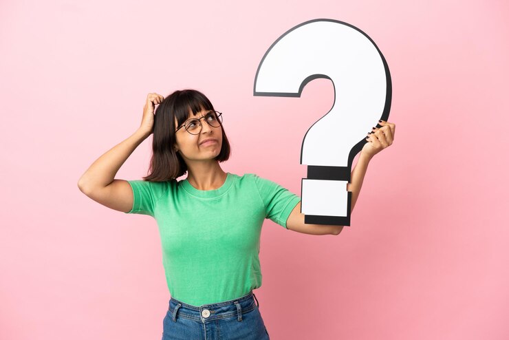 Foto mujer joven que sostiene un icono de signo de interrogación y tiene dudas