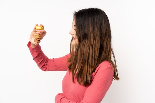 Mujer joven que sostiene macarons sobre aislado