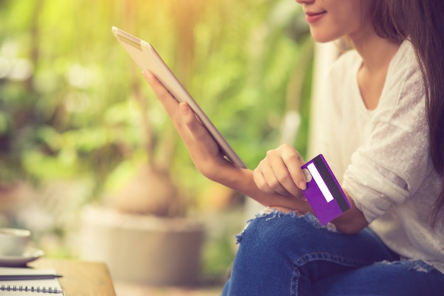 Foto mujer joven que sostiene la tarjeta de crédito y que usa la computadora portátil. concepto de compra en línea