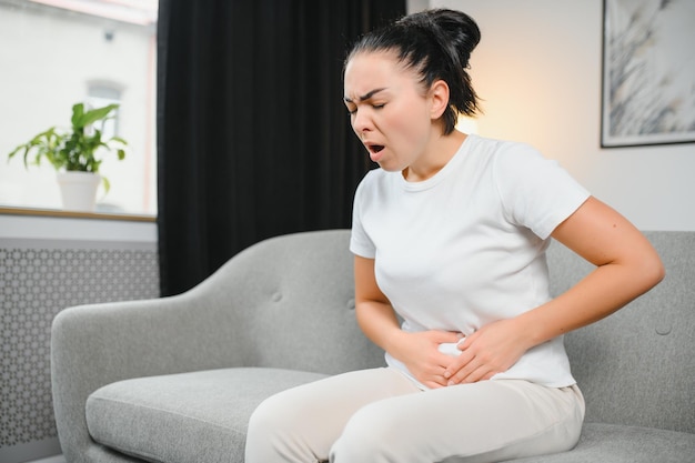 Mujer joven que sufre de calambres menstruales en casa Ginecología