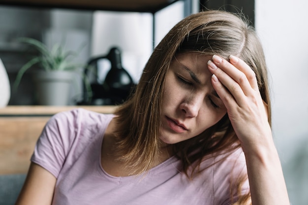 Foto mujer joven que sufre de dolor de cabeza