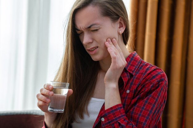 Mujer joven que sufre y experimenta dolor de muelas fuerte