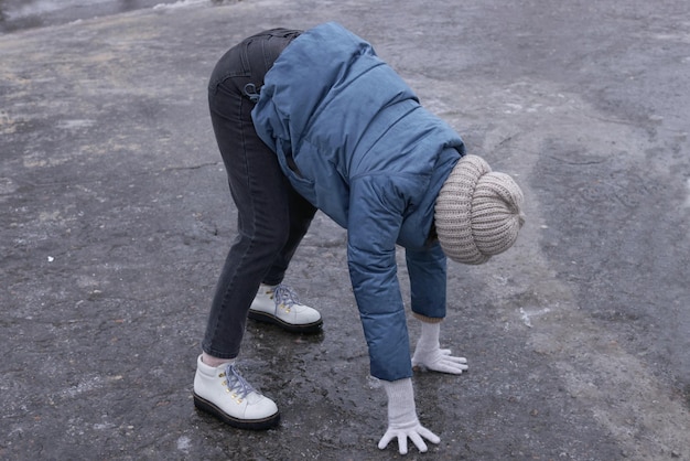 Mujer joven que tiene dificultades para moverse en un camino helado al aire libre