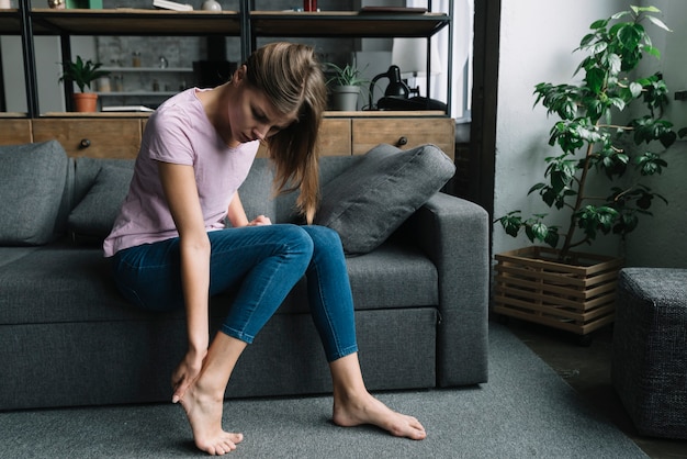 Foto mujer joven que tiene dolor en el talón del pie