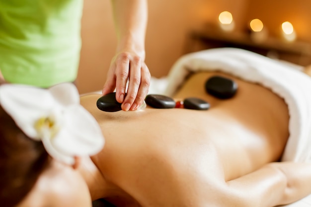 Foto mujer joven que tiene una terapia de masaje con piedras calientes