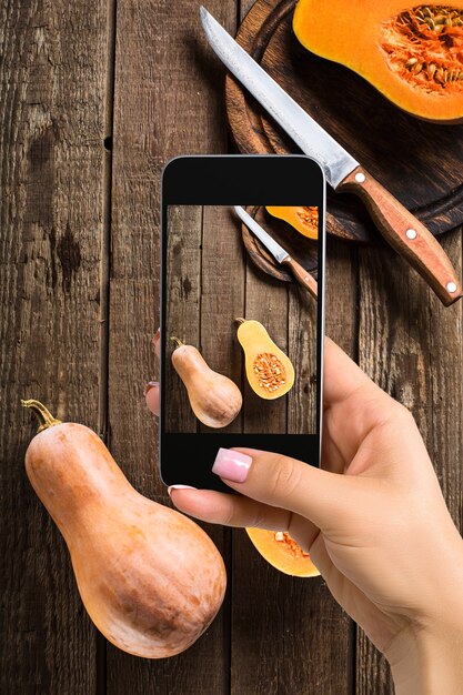 Una mujer joven que toma la foto de la comida en el teléfono inteligente, fotografia la comida con la cámara del móvil. Hecho para redes sociales. Vista superior del teléfono móvil