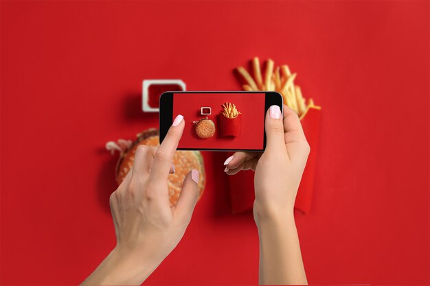 Una mujer joven que toma la foto de la comida en el teléfono inteligente, fotografia la comida con la cámara del móvil. Hecho para redes sociales. Vista superior del teléfono móvil